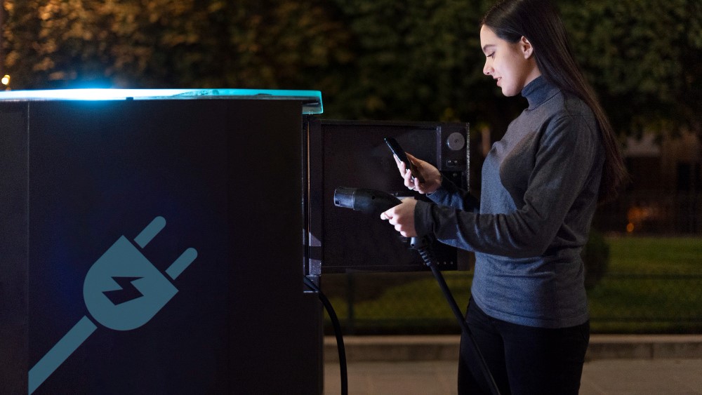 Une femme s'apprête à charger sa voiture à une borne de recharge.